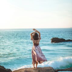Frau am Meer in entspannter Haltung – Sinnbild für Ruhe, Zyklus verstehen und hormonelle Balance im Online-Programm ZYKLUS Kompass